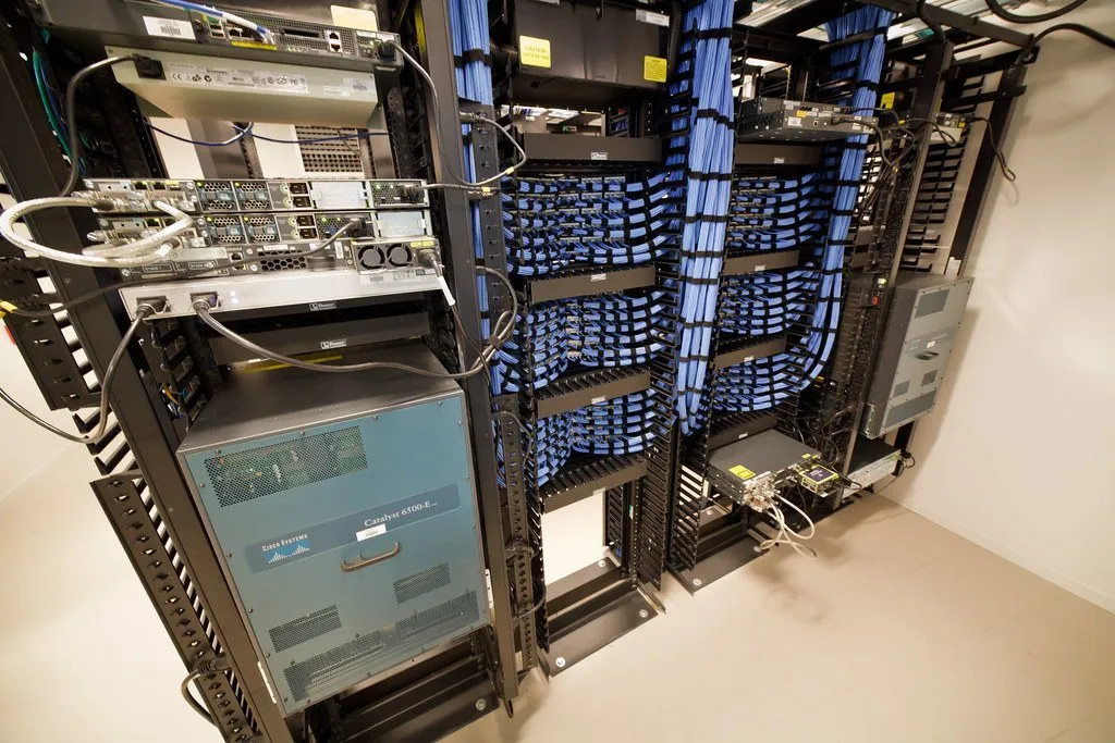 Serverkasten in een datacentrum, met honderden blauwe netwerkkabels netjes gebundeld naar een verdeelpaneel.